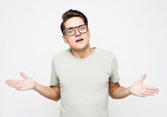 Shocked amazed surprised man wear eyeglasses standing keeping mouth open spreading hands over white...