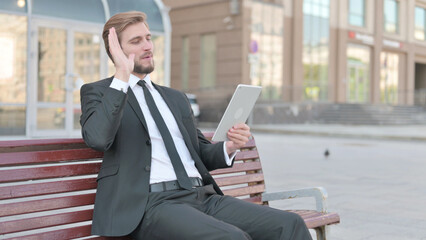 Online Video Chat on Tablet by Businessman Sitting Outdoor on Bench