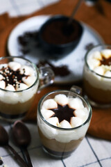Small mugs with a three-layer coffee-caramel dessert. Delicious pudding in glass cups.