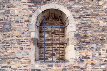 Abstract background featuring old brown stone wall with metal bars and bricked out window in...