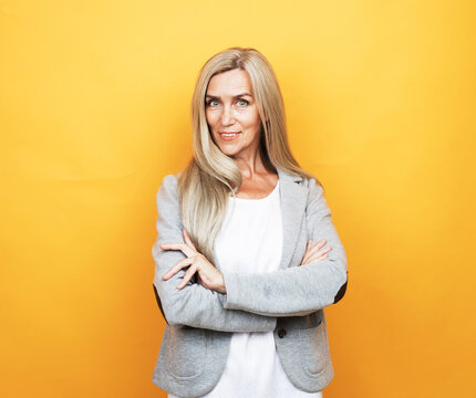 Mature Elderly Woman Standing Over Yellow Background.