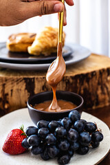 Tábua de doces com doce de leite, uva, morango, croissant, donut e drink