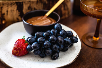 Tábua de doces com doce de leite, uva, morango, croissant, donut e drink