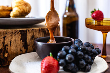 Tábua de doces com doce de leite, uva, morango, croissant, donut e drink