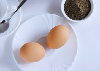 Boiled two eggs on a white plate in bright light. Shallow depth of field