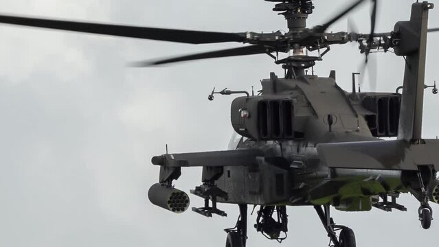 detailed close-up rear three -quarter view of ZM707 British army Boeing Apache Attack helicopter gunship (AH-64E AH64E) flying low to land amongst woodland, Wilts UK