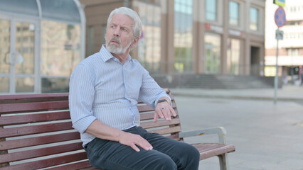 Waiting Old Man Checking Time on Watch while Sitting Outdoor on Bench