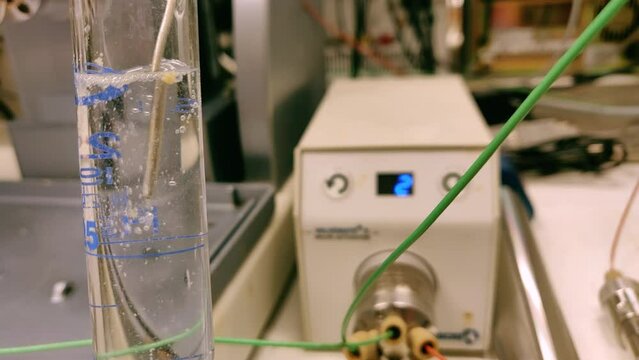 Nitrogen bubble through organic solvent in measuring cylinder in a chemistry lab for education purpose. Effervescent of carbon dioxide bubble in organic layer. 4K scientific background concept.