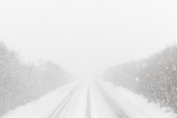 Heavy snowfall on the highway. Dangerous winter weather with low visibility. Small car on the...