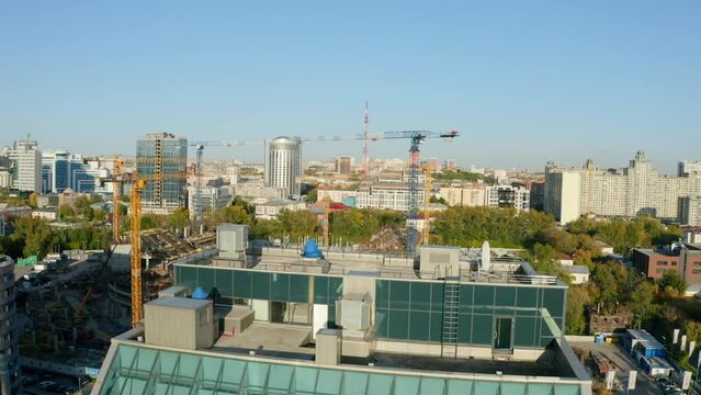 Top view of stadium construction in city. Stock footage. Construction of modern sports stadium. Cranes on construction site with oval stadium