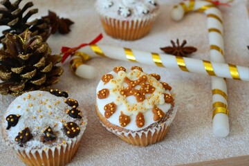 Christmas composition: Christmas cupcakes decorated with icing and surrounded by cinnamon sticks and star anise on a background of powdered sugar