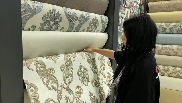 Woman in a wallpaper store examines beautifully designed textures for a home