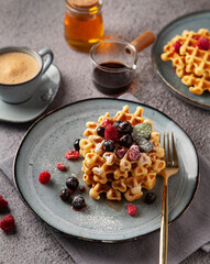 Breakfast with coffee and traditional Belgian waffles with berries on the grey table