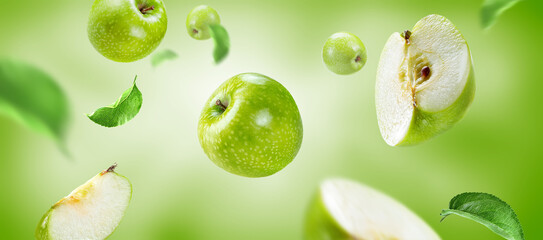 Ripe green apples and slices flying on green background 