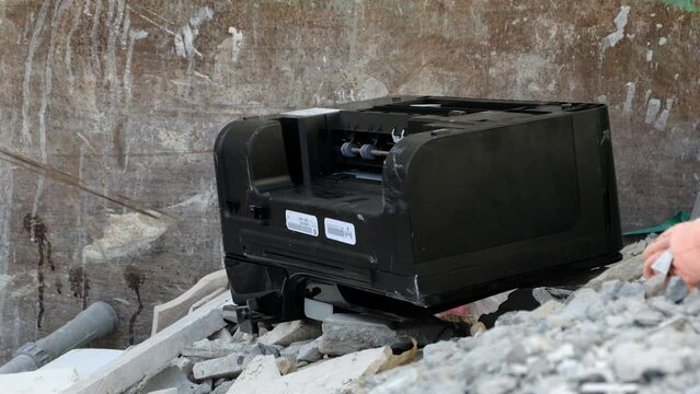 an old printer falls thrown away into a dumpster container with building waste. Broken Used Electronic rubbish. E-waste
