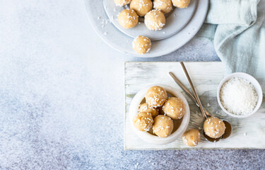 Traditional Indian festival sweets Laddoo or Laddu with coconut flakes on a wooden board, light...