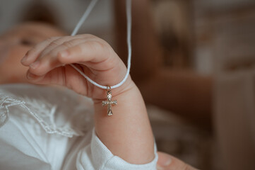 little baby hand holding a cross for baptism