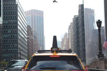 Manhattan, New York City canyon of skyscrapers street behind a yellow taxi cab