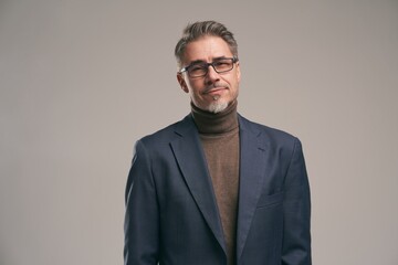 Portrait of middle aged businessman with gray hair, wearing glasses. Confident handsome mature man looking at camera on colorful background. Copy space for text.