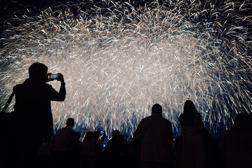 Silhouettes of people watch fireworks during the celebration. Sky full of lights