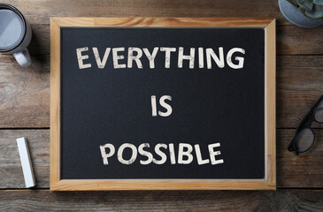 Small chalkboard with motivational quote Everything is possible, coffee, chalk and glasses on wooden table, flat lay