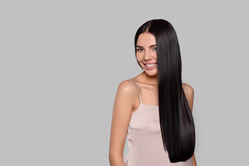 Naklejka premium Portrait of beautiful young woman with healthy strong hair on light grey background, space for text