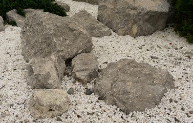 Large gray stones lie on small white pebbles and sand. Sochi, Adler.