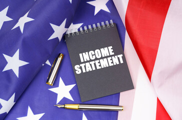 On the American flag lies a pen and a notebook with the inscription - income statement