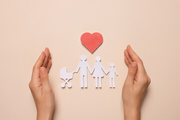 Woman protecting paper family figures and red heart on beige background, top view. Insurance concept