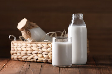 Tasty fresh milk in bottles and glass on wooden table
