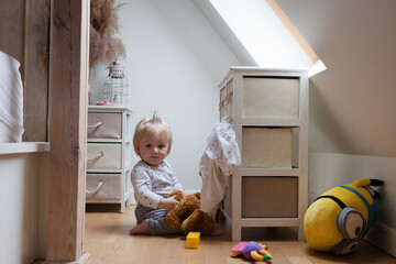 child in messy room. toddler one year old baby boy with funny facial expression playing in bedroom