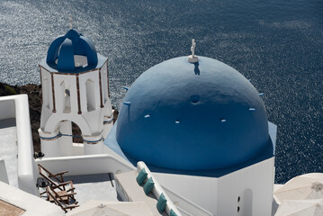 Oia, Santorini, Greece. 2022. Blue domed churches with cross and a backdrop of the Aegean Sea,