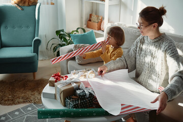 Decorating Christmas gifts, family mother and child wrapping Christmas gift box together