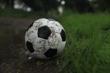 Dirty leather soccer ball near puddle outdoors