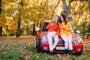 Fototapeta na wymiar girls walking in autumn park in red car, autumn mood concept