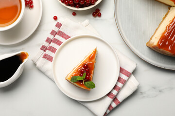 Piece of delicious caramel cheesecake with red currants and mint served on white marble table, flat...