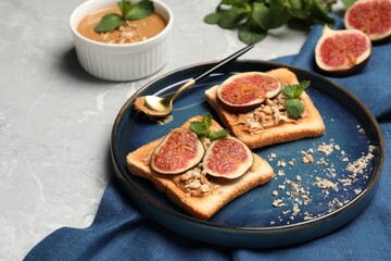 Tasty toasts served with fig, peanut butter and walnuts on light grey marble table