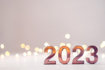 Metal numbers 2023 on a white table with bokeh lights. Happy New Year 2022 is coming concept.