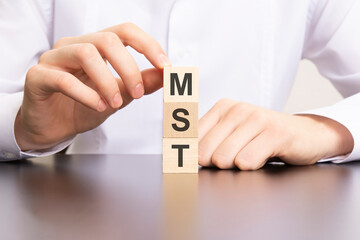 mst, Marketing Solutions and Technologies text on cube blocks in businessman hands, man in white shirt