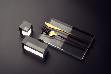 Haute cuisine concept with a golden cutlery on a glass podium on a dark background. Restaurant...