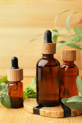 Bottles of essential oils and fresh herbs on wooden table