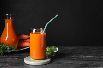 Tasty carrot juice on black marble table, space for text