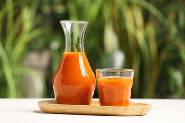 Tasty carrot juice on white table outdoors, closeup