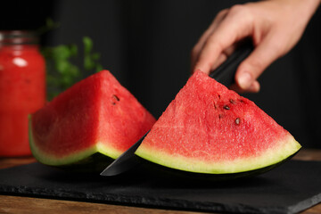 Woman cutting delicious watermelon on slate board, closeup