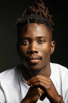 Dark studio portrait of black man in white shirt staring at camera