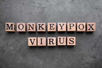 Words Monkeypox Virus made of wooden cubes on grey table, flat lay