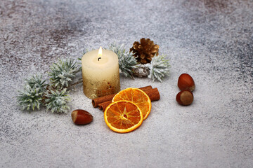 Orangenscheiben, Nüsse und Zimtstangen mit einer Aromakerze Weihnachtsduft.