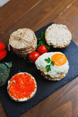 Diet rice breads, cherry tomatoes and fresh caviar and parsley on a dark background. Snack bread. View from above. Dietary fiber. Healthy Eating