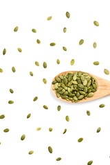 Pumpkin seeds on white background, top view. Pumpkin seeds in wooden spoon. Healthy eating