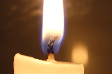 Die Flamme einer Kerze verbreitet eine warmen, romantischen Lichtschein - Makroaufnahme.
